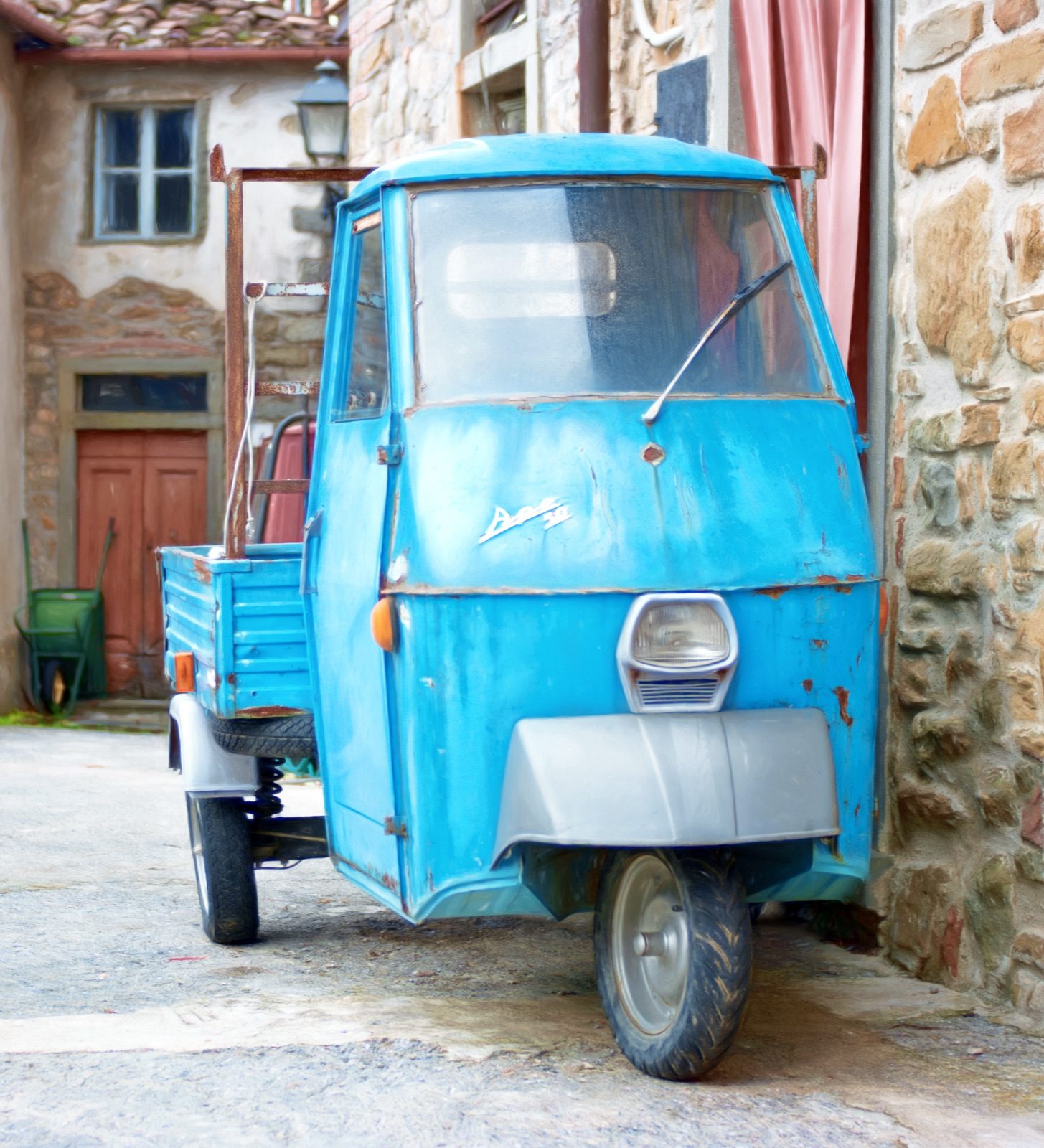 A little blue Ape van parked in a stone lane in Aramo