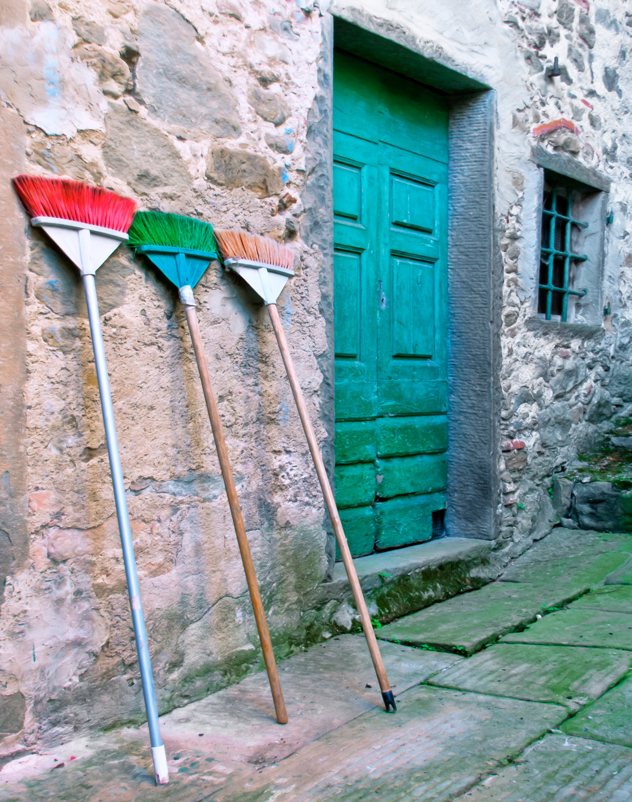 Old brooms propped beside a green door in Castelvecchio