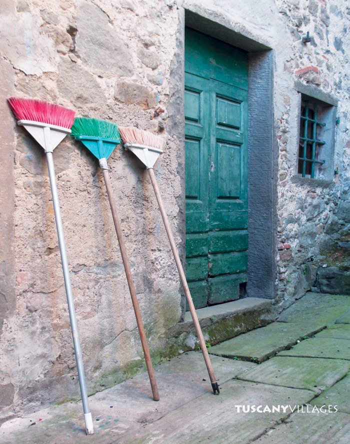 Old brooms propped beside a green door in Castelvecchio