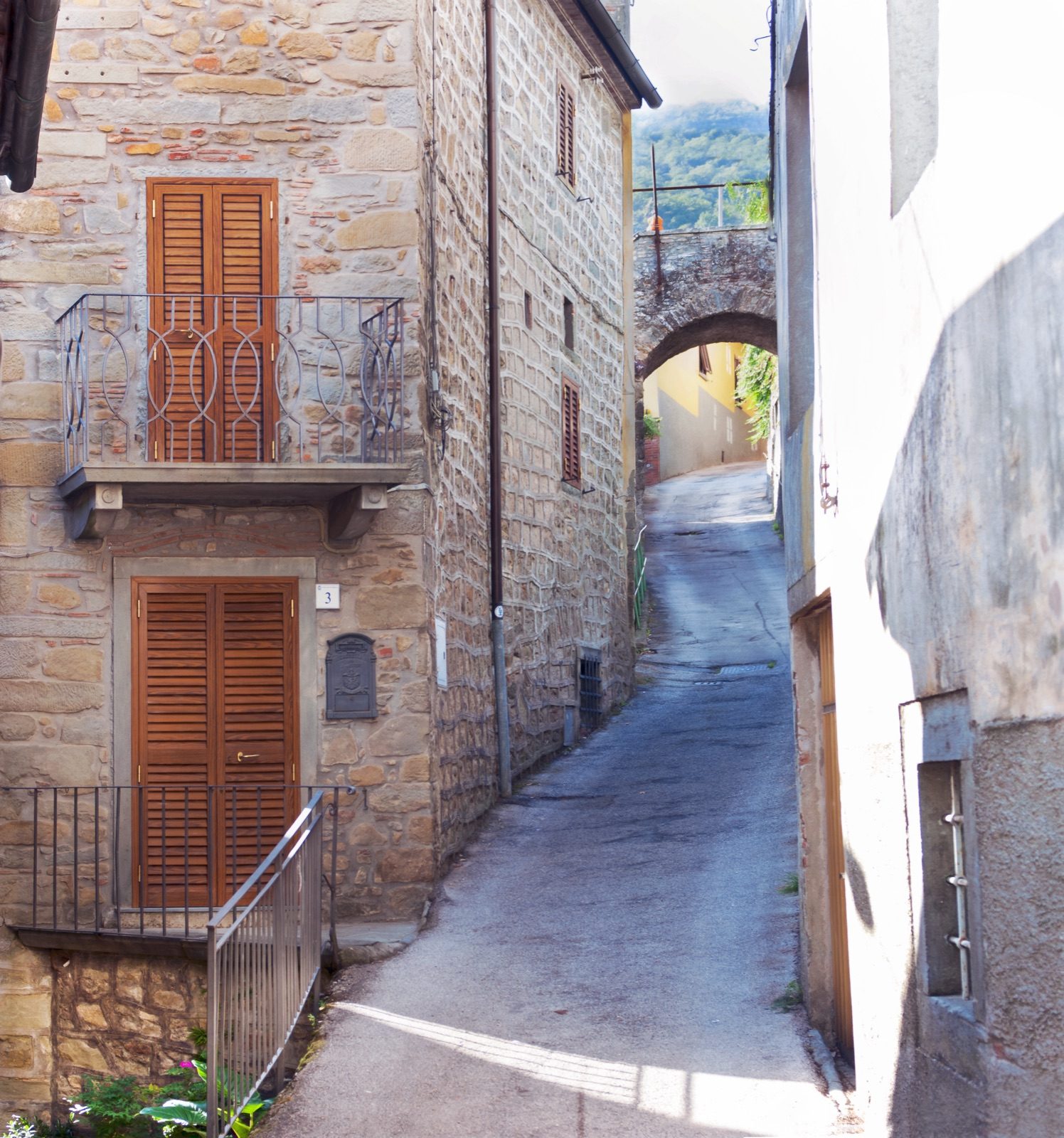 A narrow lane of old stone houses leading to an archway in Castelvecchio