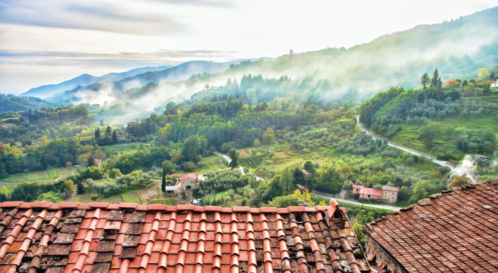 Terracotta rooftops of Castelvecchio above a misty valley