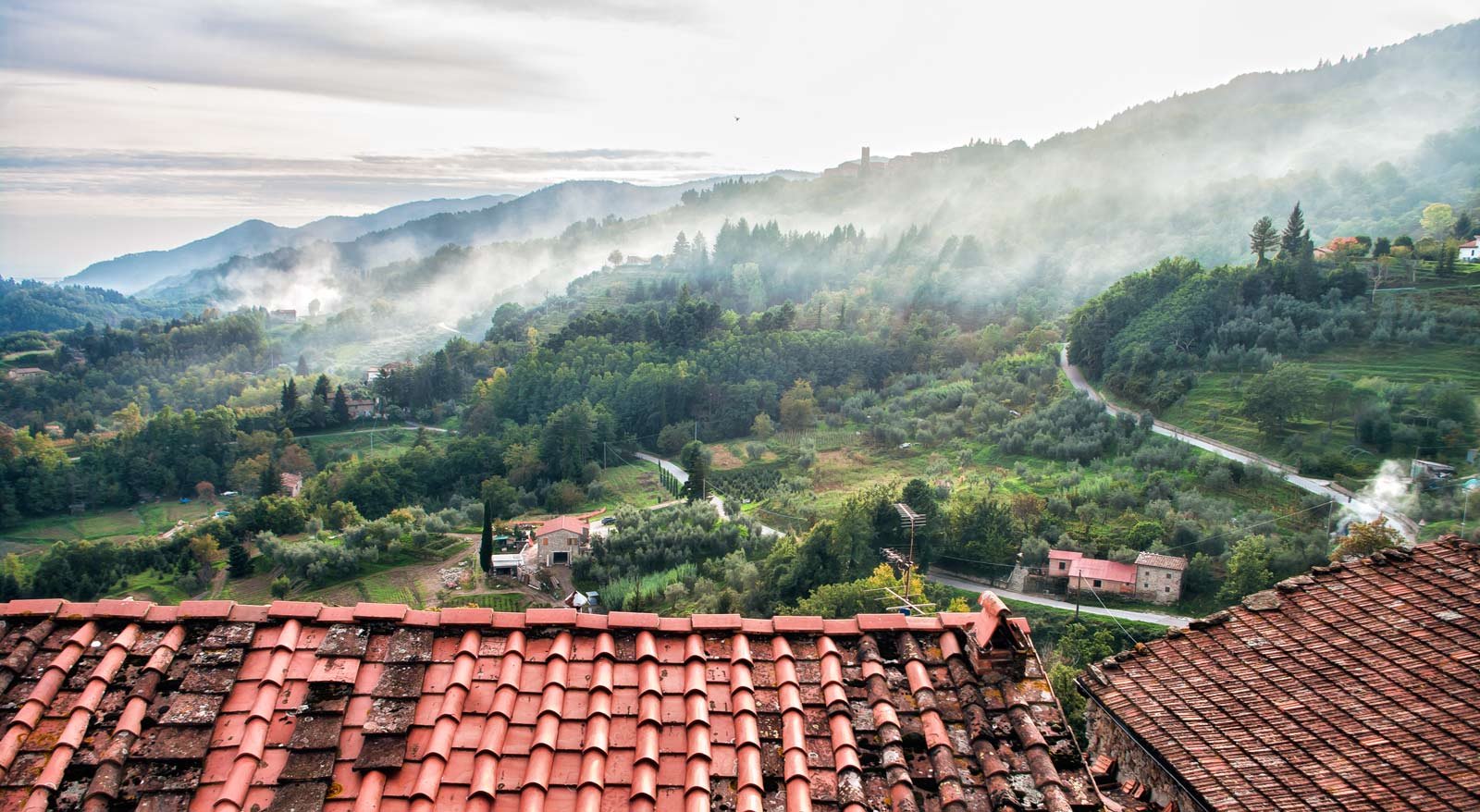 Terracotta rooftops of Castelvecchio above a misty valley