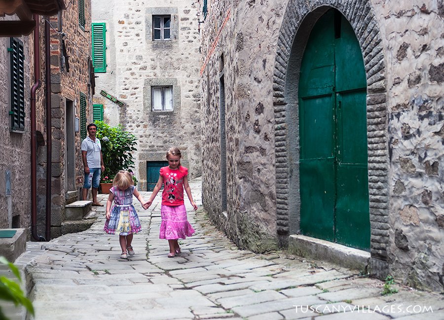 Two young sisters walking hand in hand up a lane in Stiappa