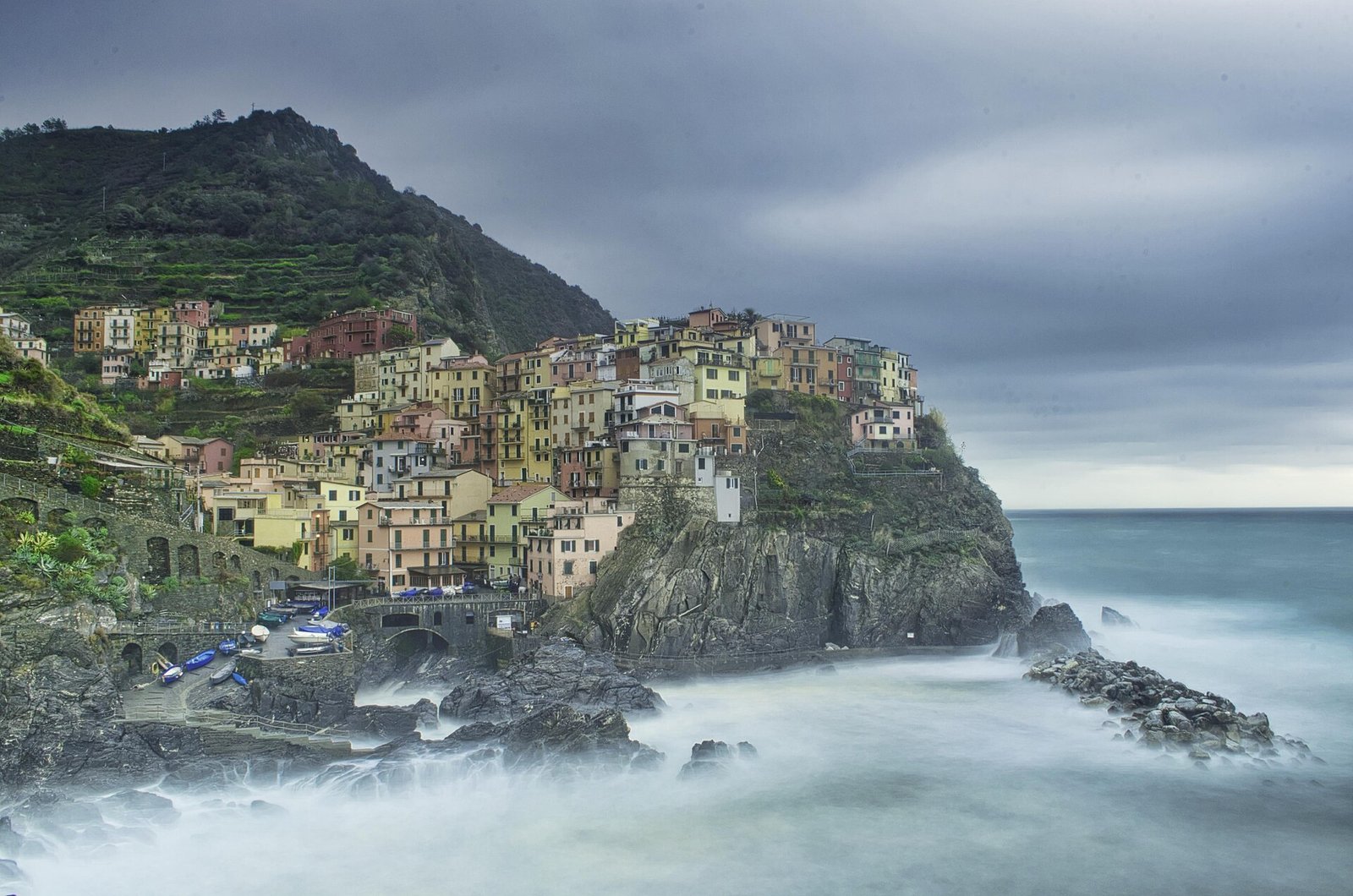 Manarola's houses stacked on dark rocks above a misty winter sea