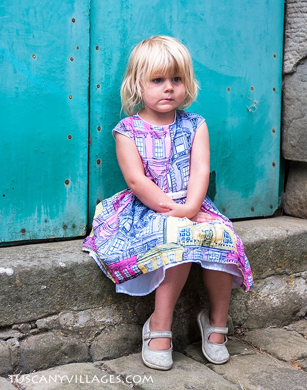 A young girl sitting on a stone step in Fibbialla
