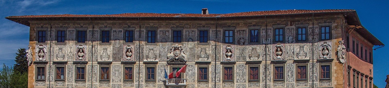 The upper floors of the Palazzo della Carovana in Pisa, covered in black and white graffito decoration and carved busts
