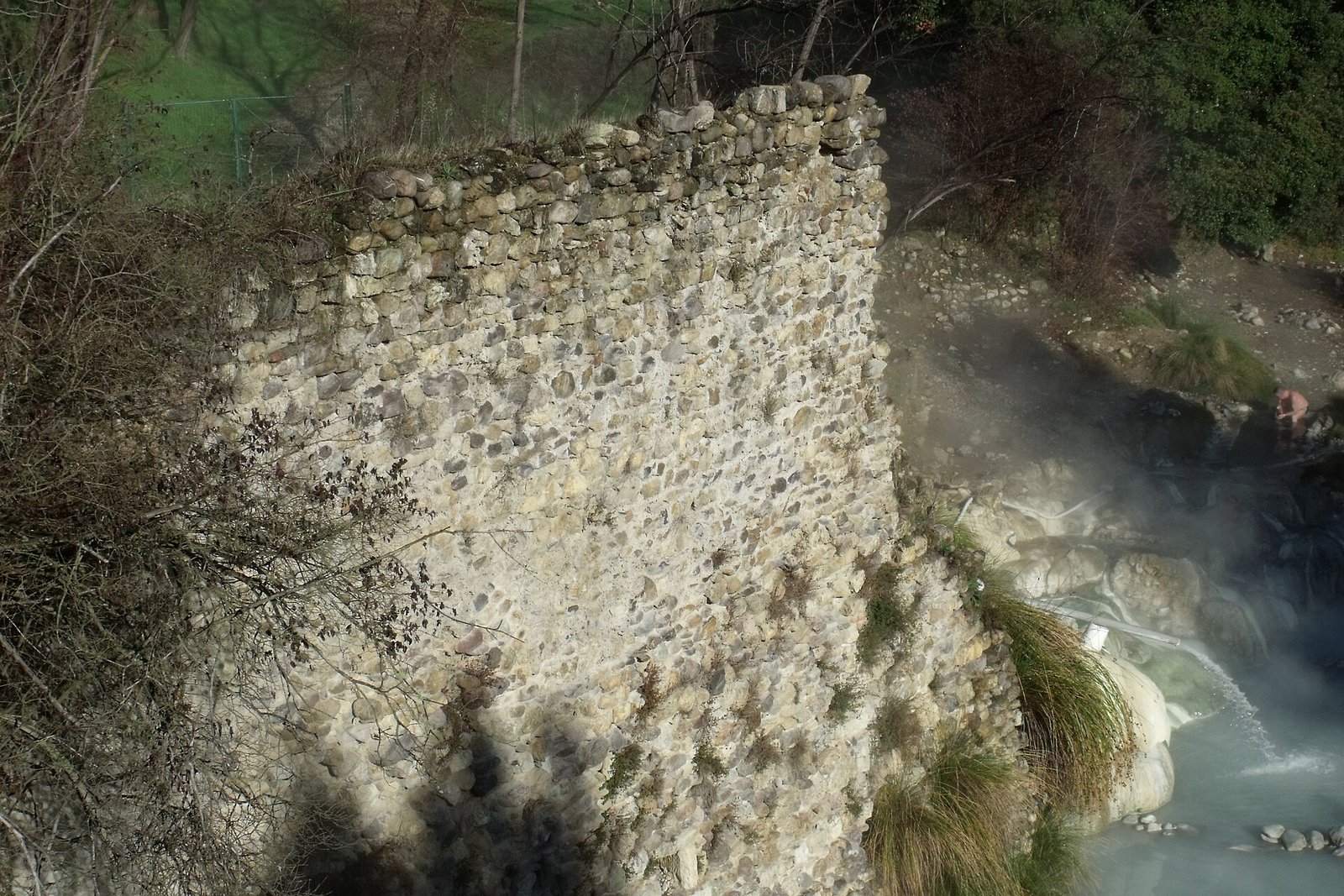 Steaming thermal water by the old walls of the Bagni di Petriolo, beside the river Farma