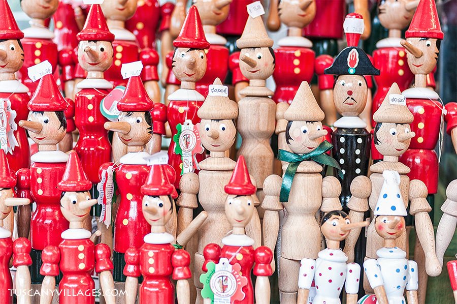 Rows of wooden Pinocchio puppets in red hats