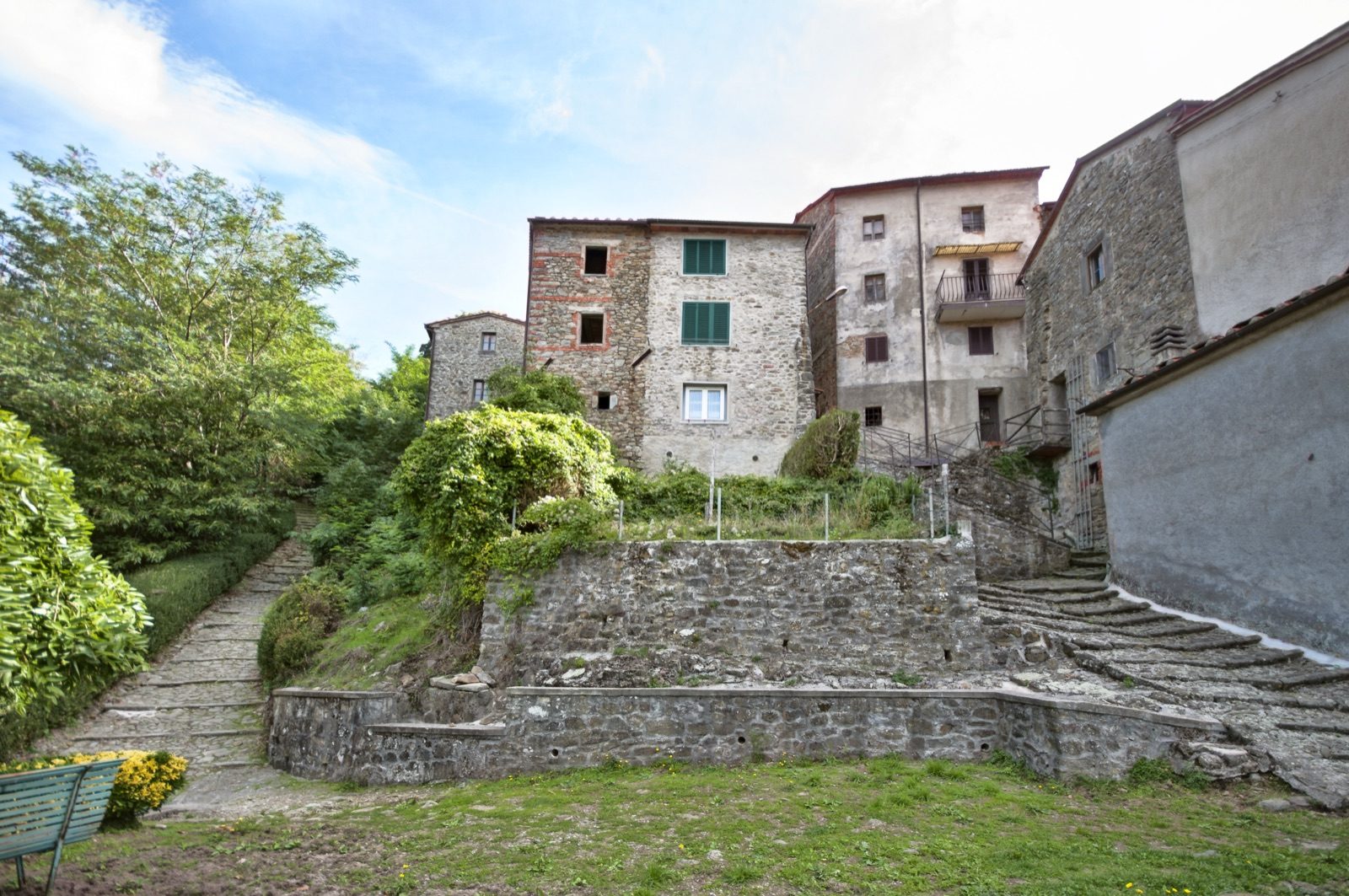 Stone steps climbing past a grassy terrace to the tall old houses of Pontito