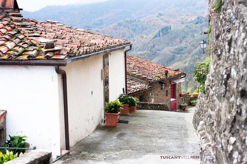 Rooftops and a red door in San Quirico with a view across the valley