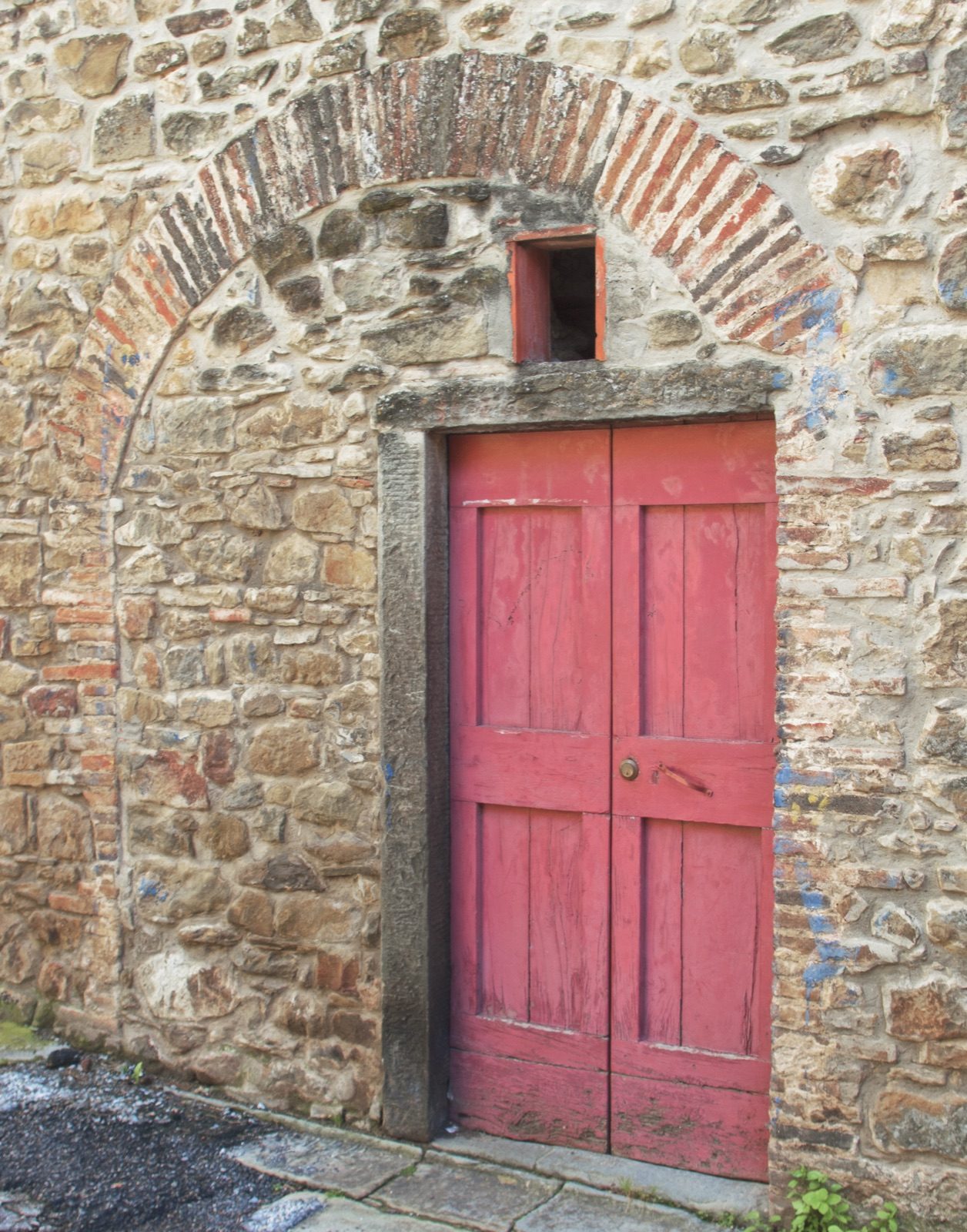 A red door set in an old stone arch in Sorana