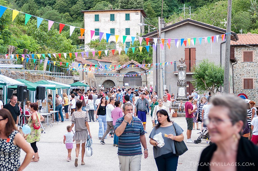 The piazza in Stiappa full of people, bunting and stalls on festa day