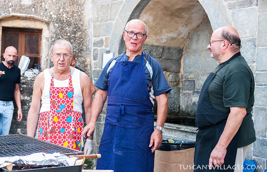 Men in flowery aprons cooking at the festa barbecue