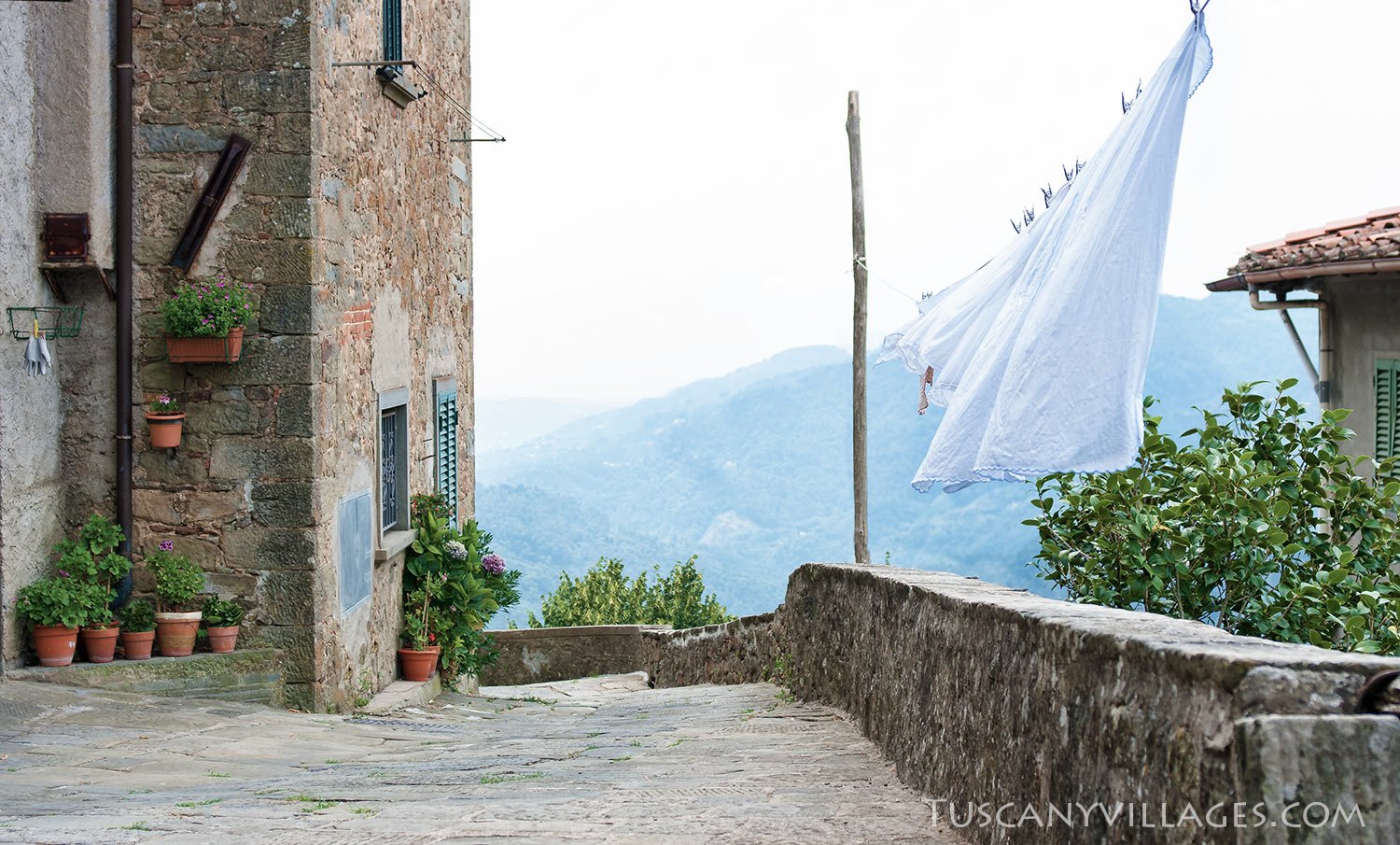 A stone lane in Vellano with washing on a line and the valley beyond