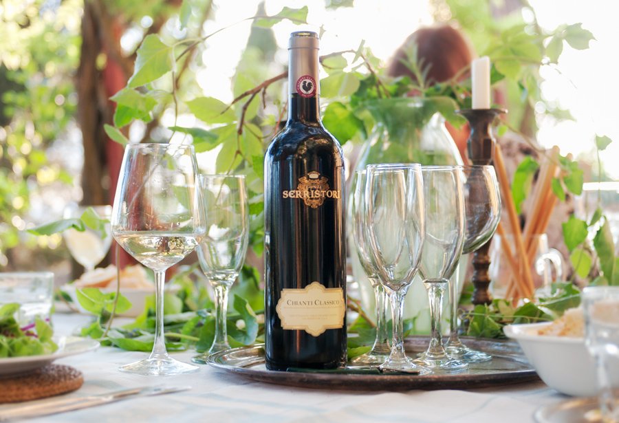 A bottle of Chianti Classico and glasses on a table outdoors